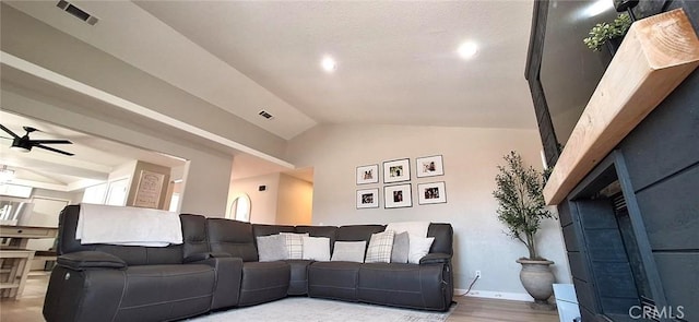 living area featuring ceiling fan, visible vents, vaulted ceiling, baseboards, and wood finished floors