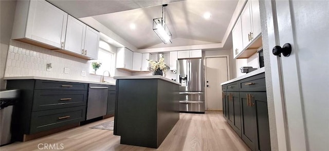 kitchen with stainless steel appliances, light wood finished floors, lofted ceiling, and decorative backsplash