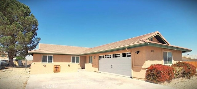 ranch-style home with driveway, a garage, stucco siding, and fence