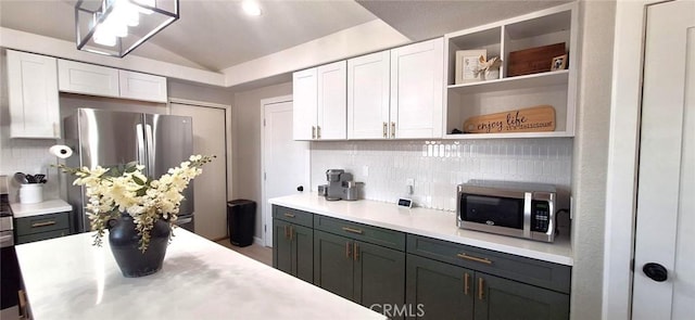 kitchen featuring stainless steel appliances, white cabinets, vaulted ceiling, and backsplash