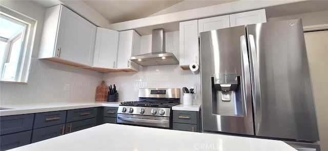 kitchen with backsplash, wall chimney range hood, light countertops, white cabinets, and appliances with stainless steel finishes