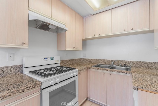 kitchen featuring a sink, light brown cabinets, gas range gas stove, and under cabinet range hood