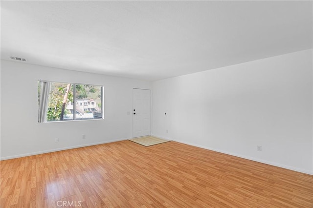 unfurnished room featuring visible vents, light wood-style floors, and baseboards