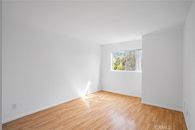 unfurnished room with baseboards and wood finished floors