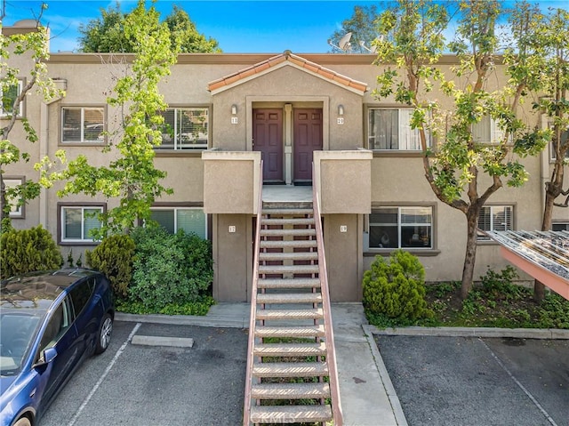 view of property with stairs and uncovered parking