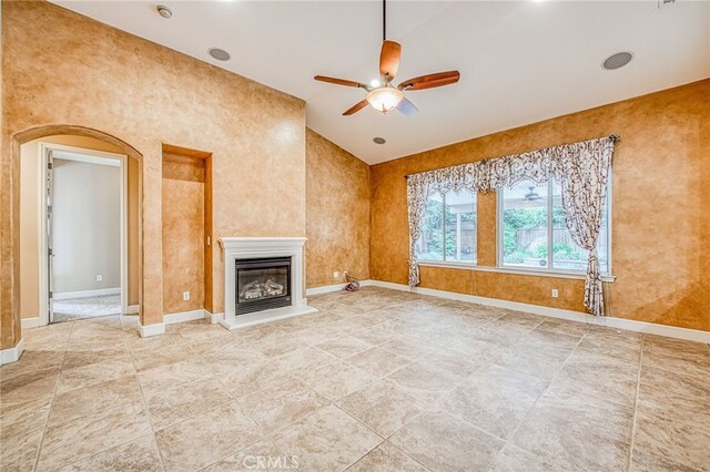 unfurnished living room featuring a ceiling fan, baseboards, and a glass covered fireplace