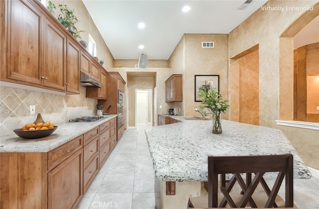 kitchen featuring a sink, under cabinet range hood, visible vents, backsplash, and appliances with stainless steel finishes