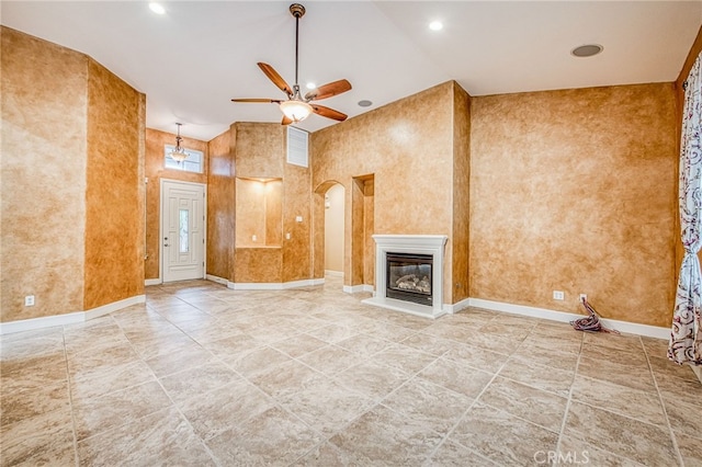unfurnished living room featuring arched walkways, a glass covered fireplace, a ceiling fan, baseboards, and tile patterned flooring