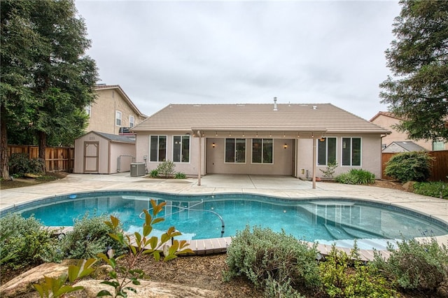 back of house featuring central air condition unit, a patio area, a fenced backyard, a tiled roof, and a storage unit