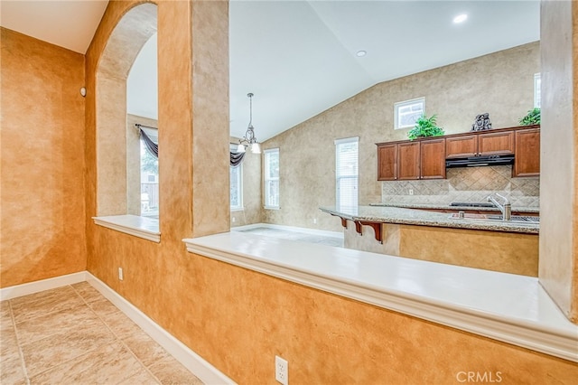 kitchen featuring a sink, brown cabinets, extractor fan, arched walkways, and lofted ceiling