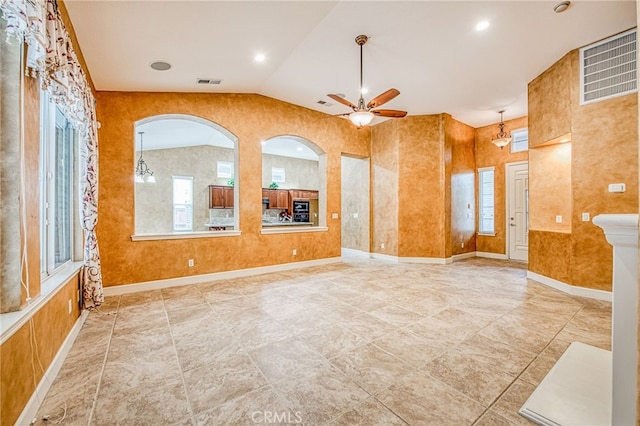 empty room featuring lofted ceiling, visible vents, a ceiling fan, and arched walkways