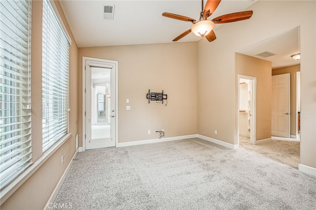 carpeted spare room featuring lofted ceiling, visible vents, ceiling fan, and baseboards