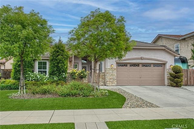 obstructed view of property featuring driveway, fence, stone siding, stucco siding, and a garage