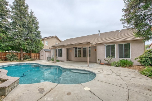 view of pool with a patio, an outdoor structure, cooling unit, a storage unit, and fence