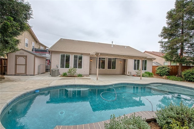 back of house featuring a tile roof, a patio, an outbuilding, a fenced backyard, and a shed