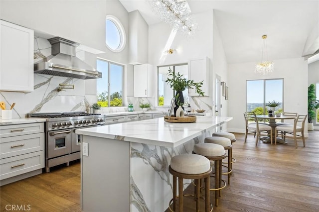 10815 San Marcos Rd, Atascadero, CA 93422 - kitchen with wall chimney exhaust hood, a chandelier, range with two ovens, light stone counters, and backsplash