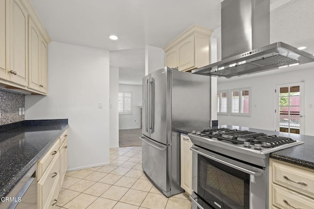 kitchen featuring wall chimney range hood, stainless steel appliances, light tile patterned floors, and cream cabinetry