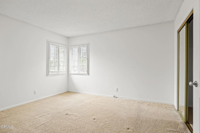 carpeted spare room with baseboards and a textured ceiling