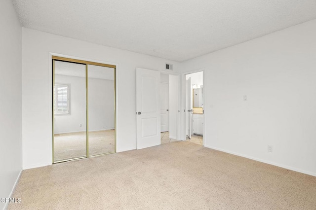 unfurnished bedroom featuring baseboards, light colored carpet, visible vents, and a closet