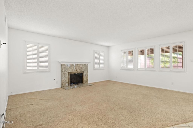 unfurnished living room featuring carpet floors, a textured ceiling, baseboards, and a fireplace
