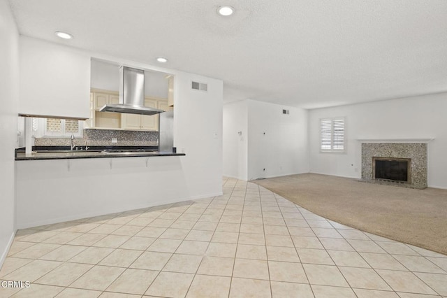 unfurnished living room with visible vents, light colored carpet, a fireplace, light tile patterned floors, and recessed lighting