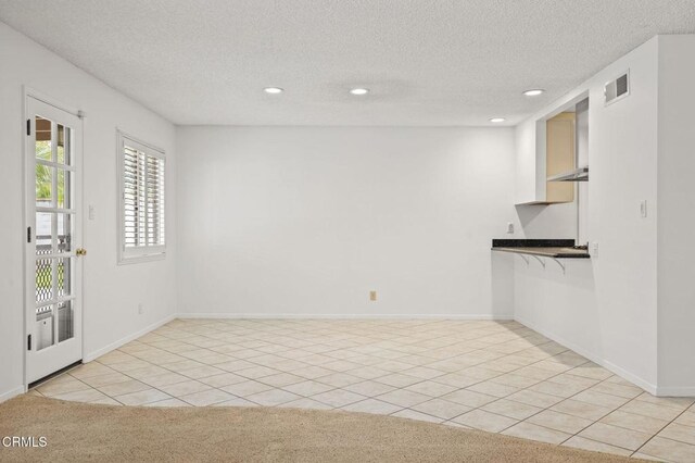 interior space featuring recessed lighting, a textured ceiling, light tile patterned floors, and visible vents