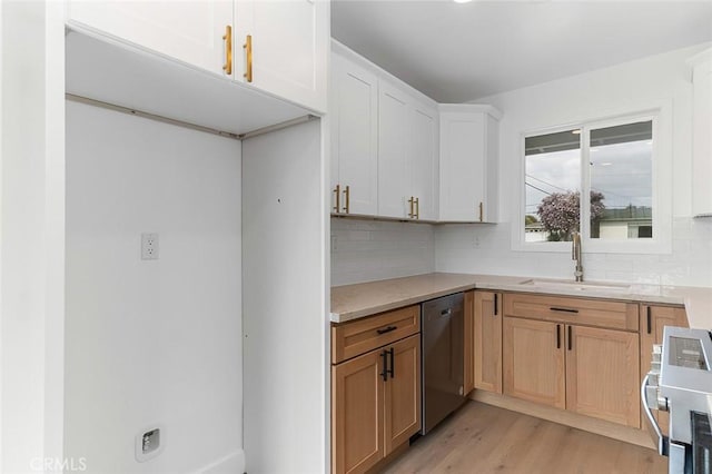 kitchen with a sink, backsplash, light wood-style flooring, light countertops, and dishwasher