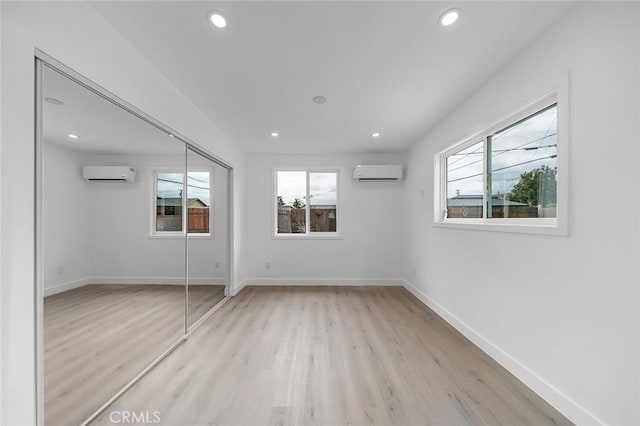 unfurnished bedroom featuring a wall mounted air conditioner, recessed lighting, baseboards, and light wood-type flooring