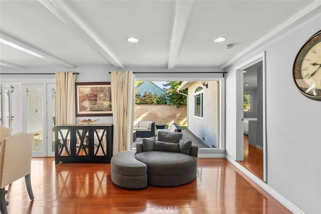 sitting room with beam ceiling, baseboards, wood finished floors, and a wealth of natural light