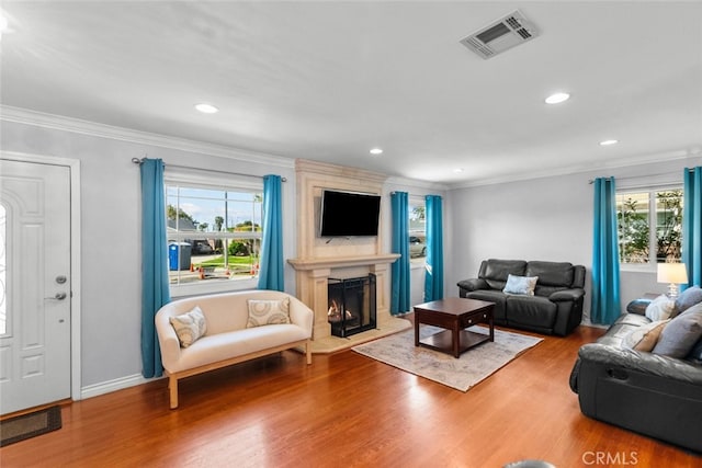 living area with recessed lighting, wood finished floors, a large fireplace, ornamental molding, and visible vents