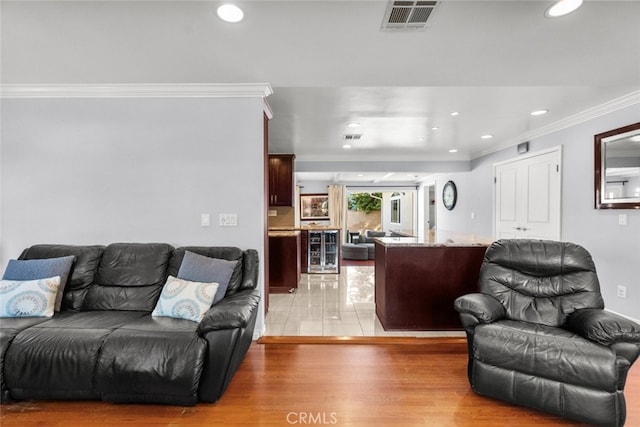 living room with crown molding, light wood-style flooring, beverage cooler, visible vents, and recessed lighting