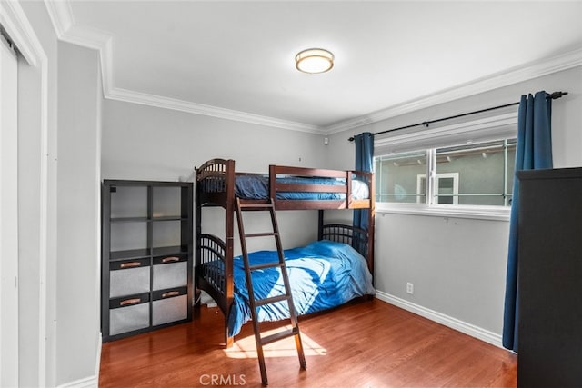 bedroom with baseboards, wood finished floors, and crown molding