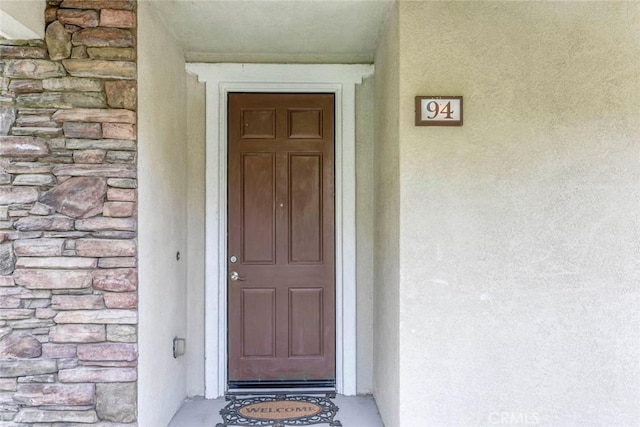 property entrance with stucco siding and stone siding