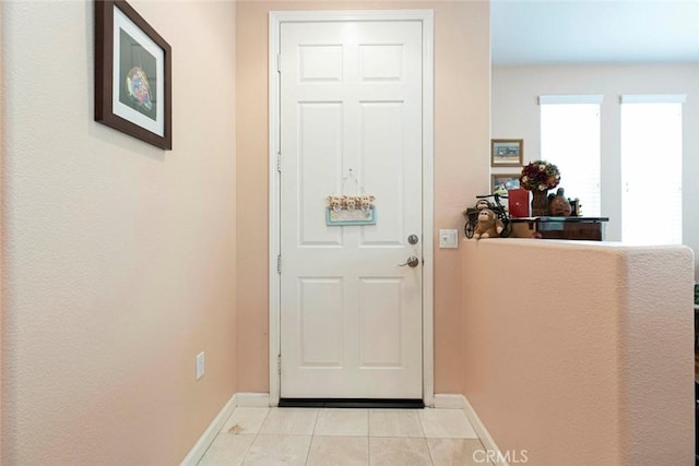 doorway to outside with light tile patterned floors and baseboards