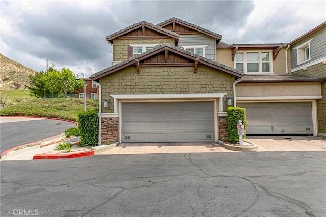 view of front of property with driveway and stone siding