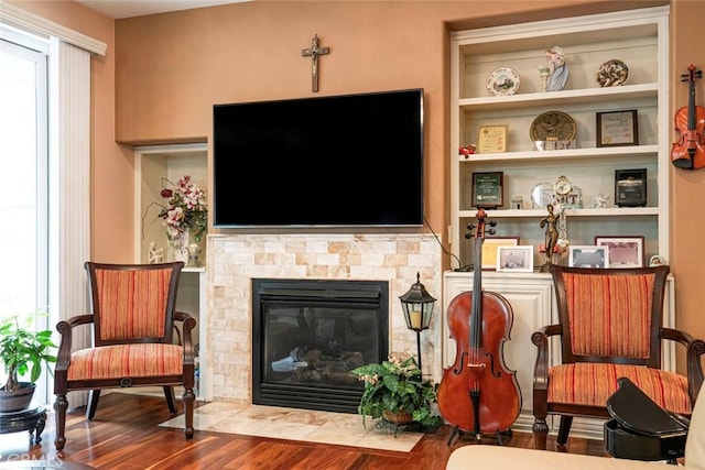 living room with a fireplace with flush hearth, built in features, and wood finished floors