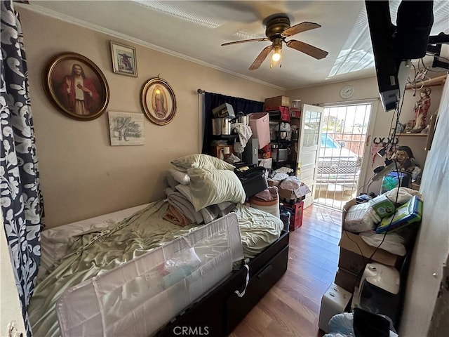 bedroom featuring a ceiling fan, access to exterior, ornamental molding, and wood finished floors
