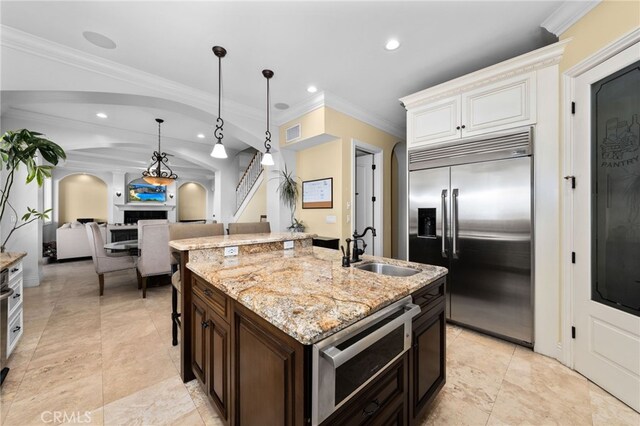 280 W 26th St, Upland, CA 91784 - kitchen with appliances with stainless steel finishes, a sink, arched walkways, ornamental molding, and a kitchen island with sink
