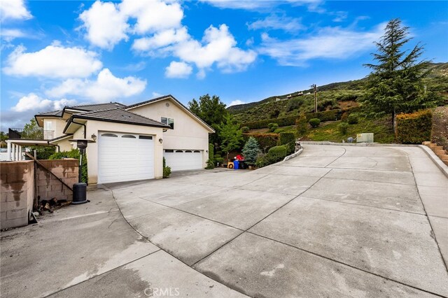 280 W 26th St, Upland, CA 91784 - view of side of home with an attached garage, concrete driveway, stucco siding, a mountain view, and a tile roof