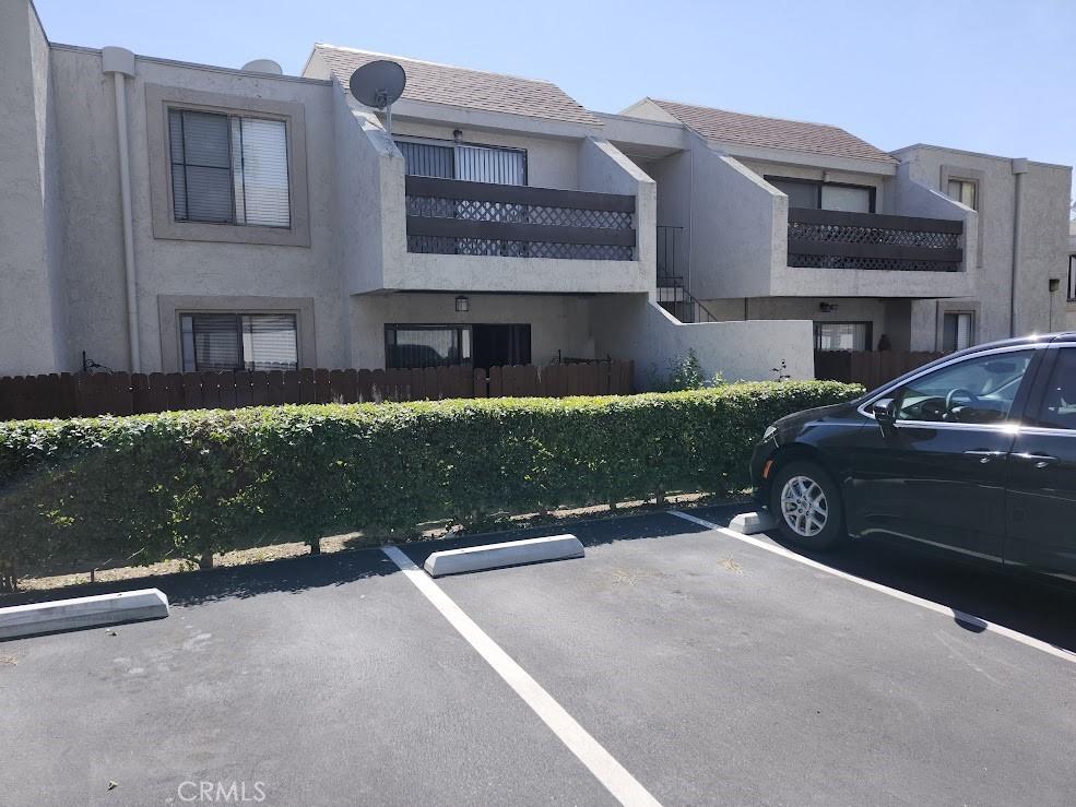 view of building exterior featuring fence and uncovered parking