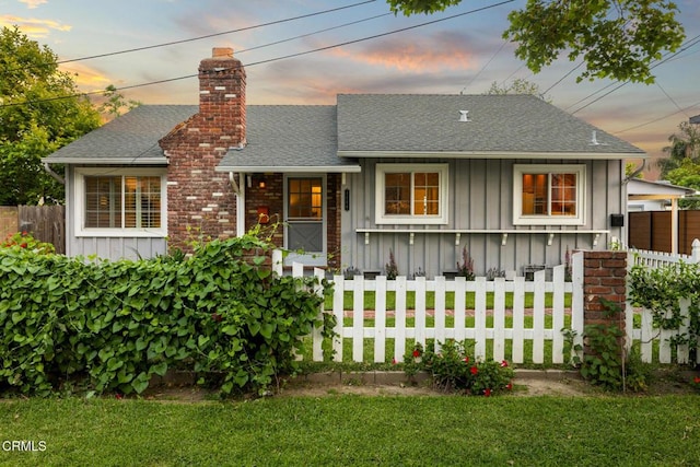 bungalow-style home featuring a lawn, board and batten siding, and fence
