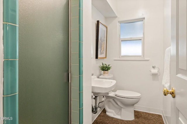 bathroom with toilet, a shower stall, and baseboards