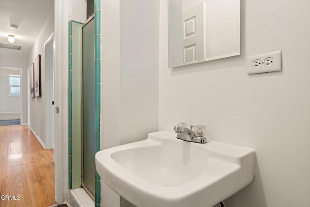 full bathroom featuring a stall shower, a sink, and wood finished floors