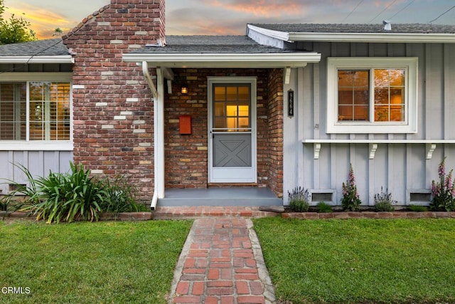 property entrance featuring a chimney, board and batten siding, and a yard