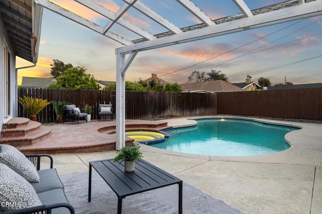 pool at dusk with a pool with connected hot tub, a patio, a pergola, and a fenced backyard