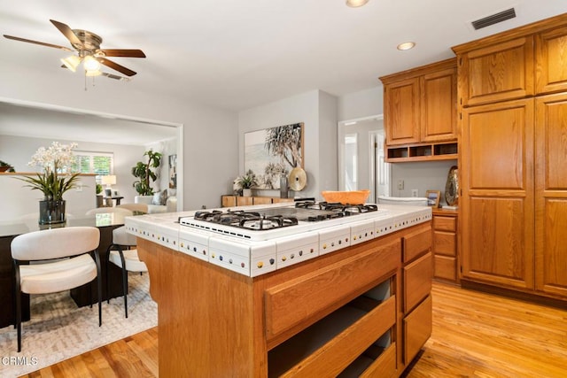 kitchen with open shelves, light wood-style flooring, white gas stovetop, recessed lighting, and tile countertops