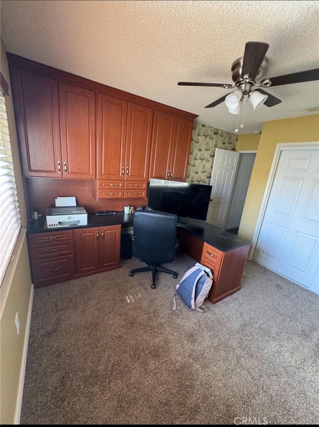 carpeted office space with baseboards, a ceiling fan, wallpapered walls, and a textured ceiling