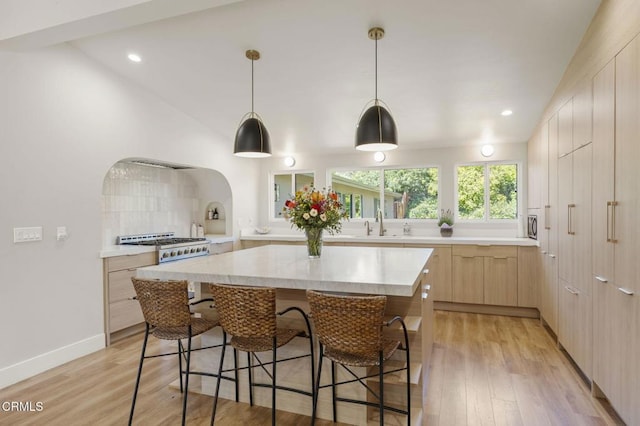 1820 Ramona Dr, Camarillo, CA 93010 - kitchen with light brown cabinetry, a breakfast bar, modern cabinets, light countertops, and arched walkways