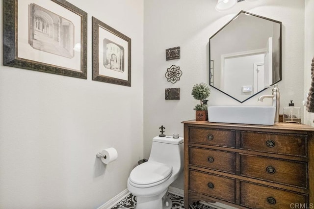 half bathroom featuring toilet, baseboards, and vanity