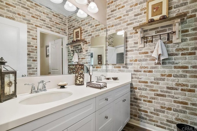 bathroom featuring a sink and brick wall
